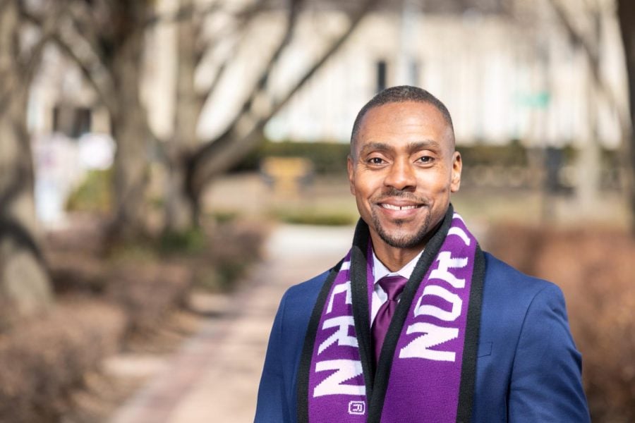 A man smiles for a photo while wearing a Northwestern scarf.