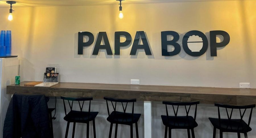 White background with the words Papa Bop written in black, large letters. A water dispenser with cups is in the corner.