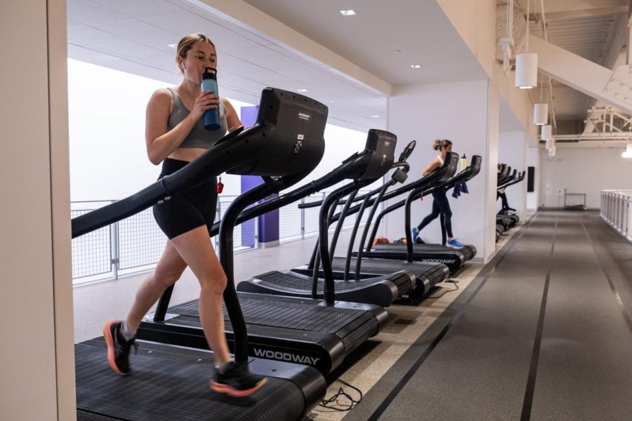 Girl runs on treadmill in black biker shorts and gray top