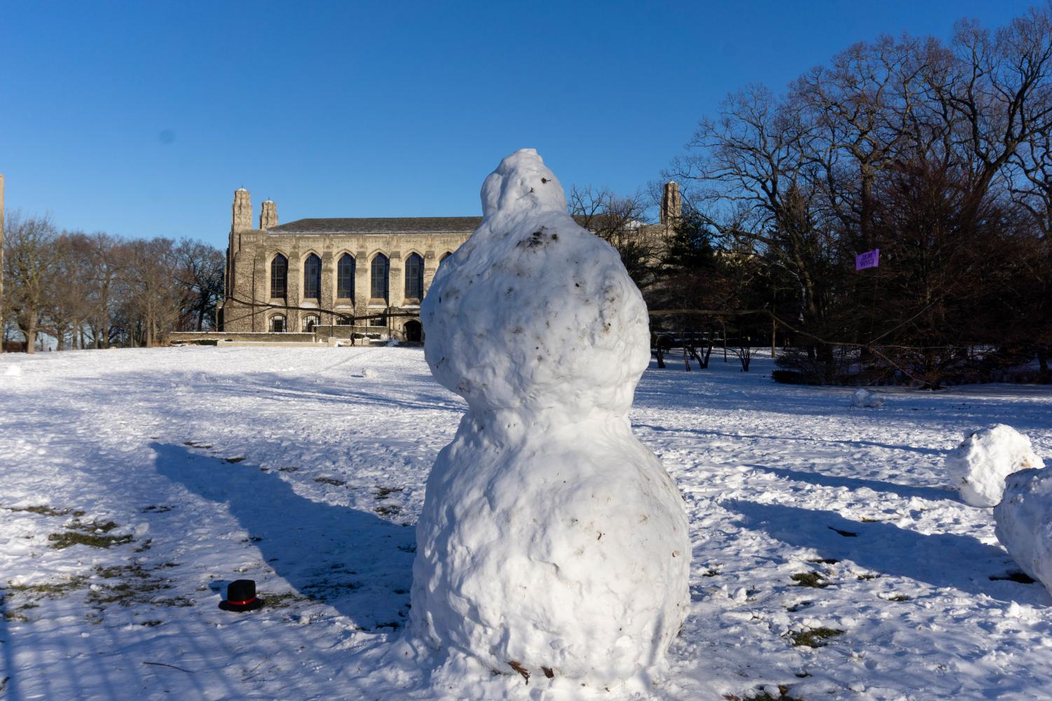 A huge snowman with stick arms outstretched.