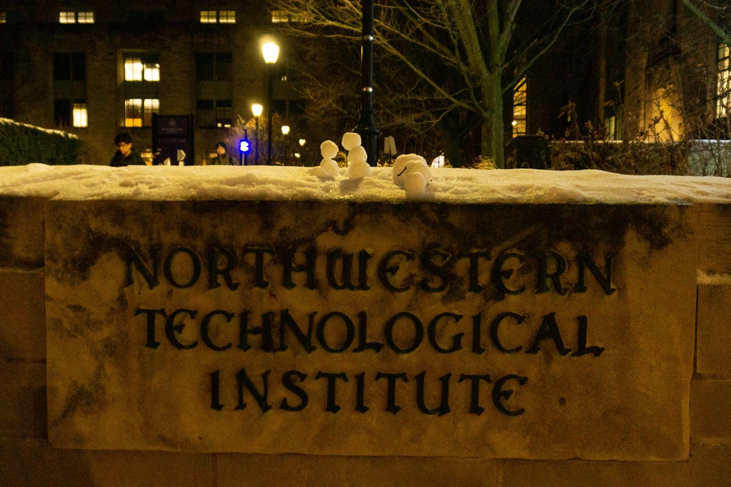 Three tiny snowmen on top of a sign that reads “Northwestern Technological Institute.”