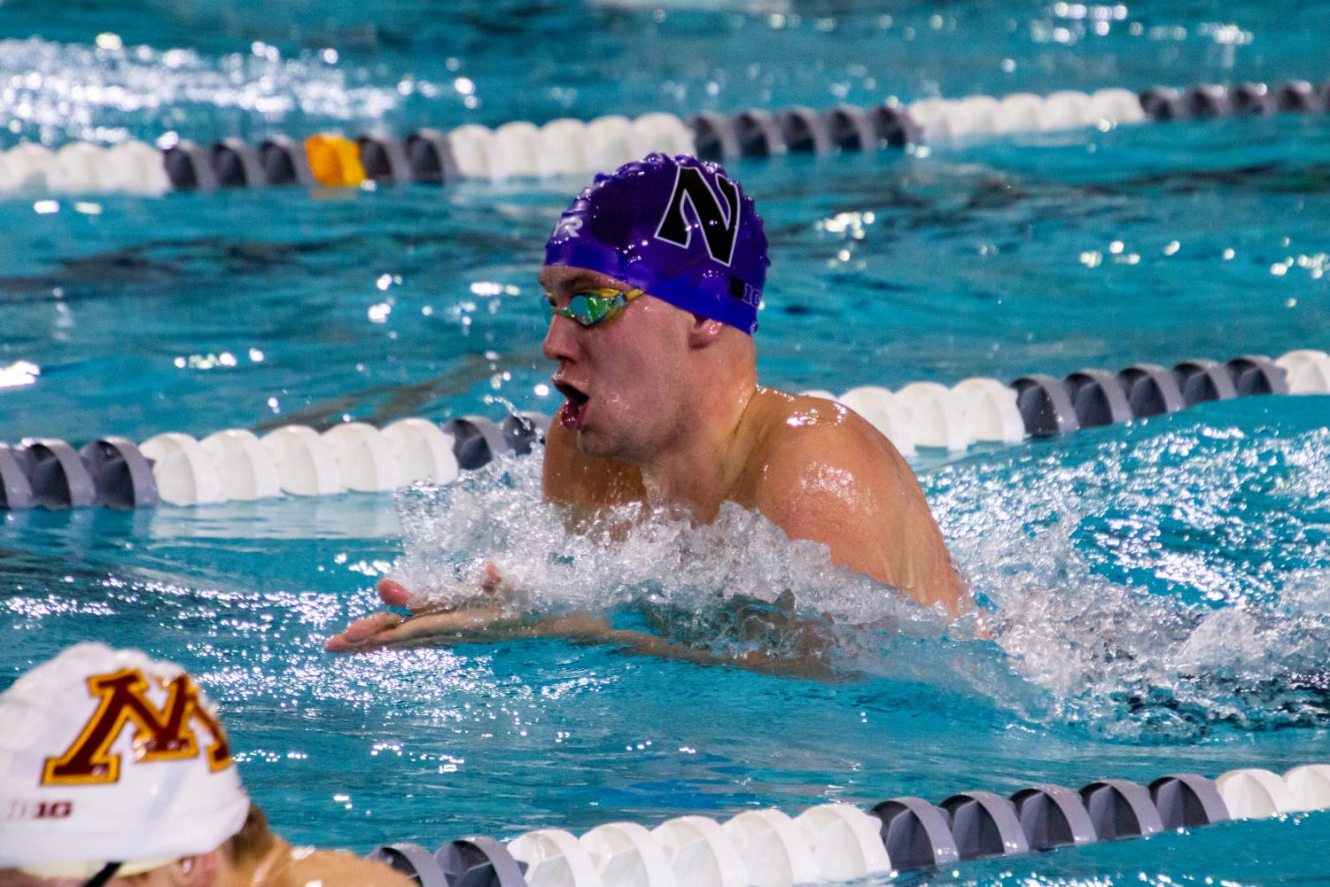 A swimmer with a purple cap comes up for a breath of air before going back into the water.
