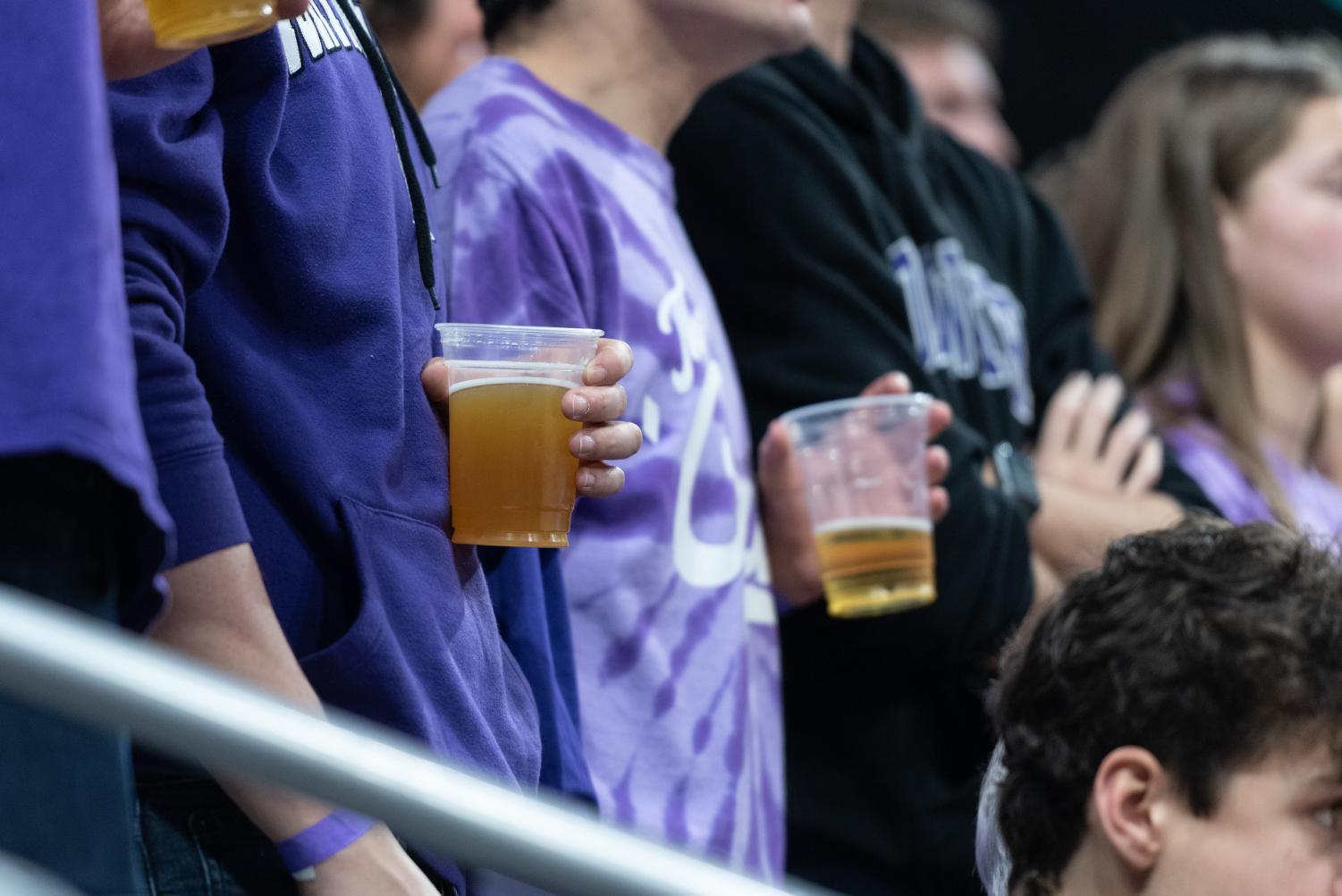 Students+in+purple+gear+hold+glasses+of+beer.