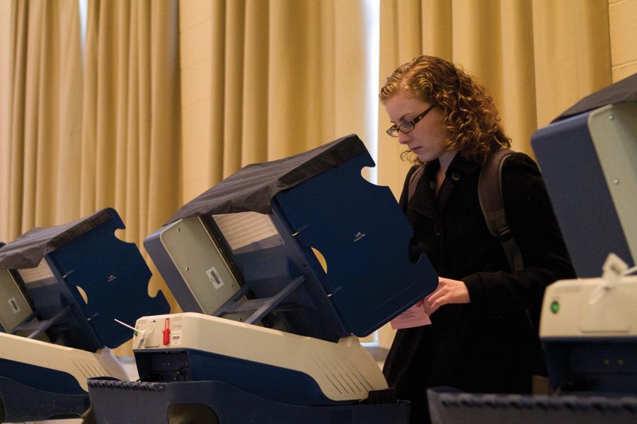 A student votes in a voting booth.