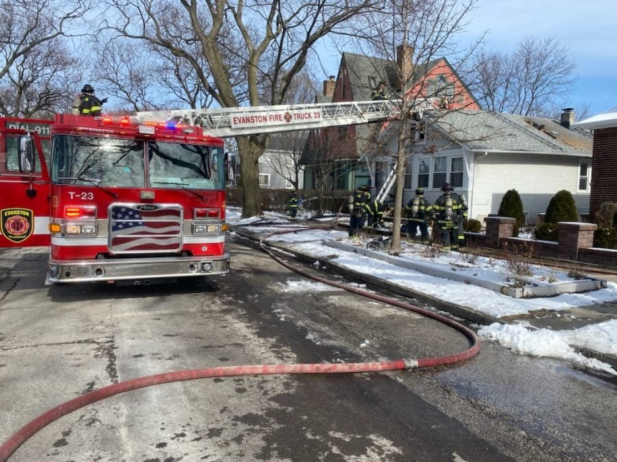 A fire truck extends an arm to the roof of a house.