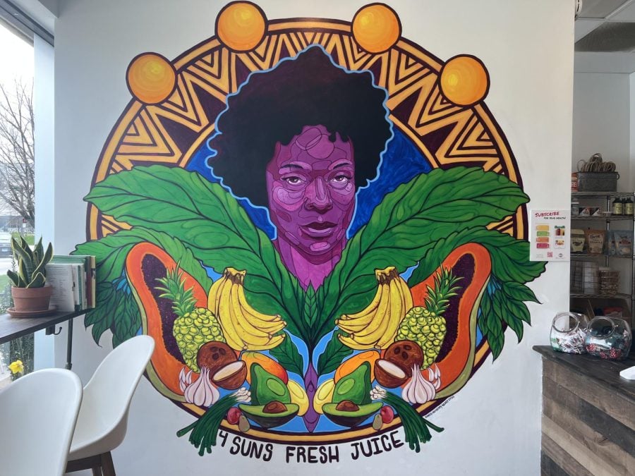 A mural depicting Owner Gabrielle Walker-Aguilar with the words “4 Suns Fresh Juice” written in black underneath.