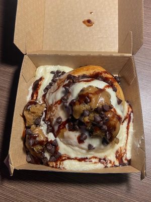Cinnamon roll with cookie dough bites, chocolate syrup and icing