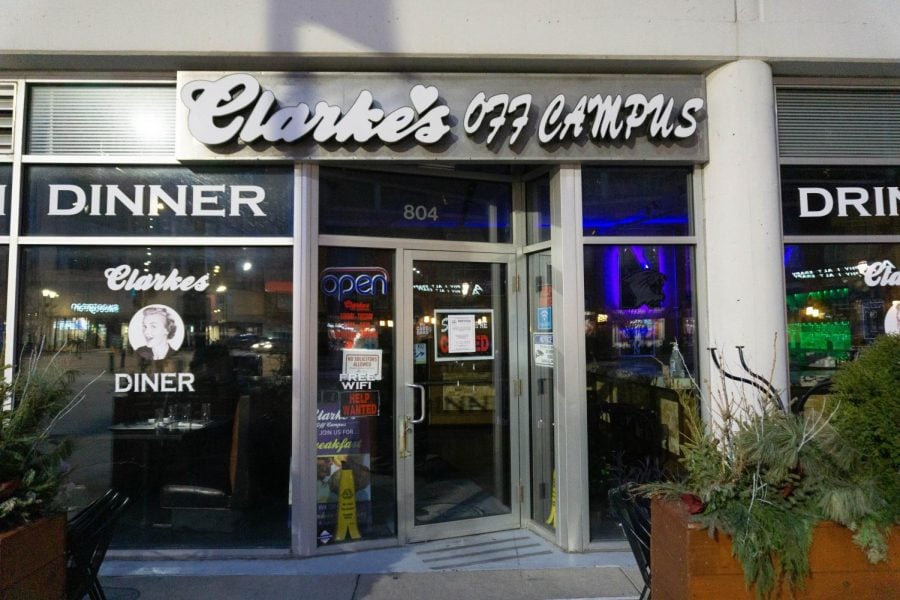 White lettering reads “Clarke’s Off Campus” over a building with floor-to-ceiling windows.