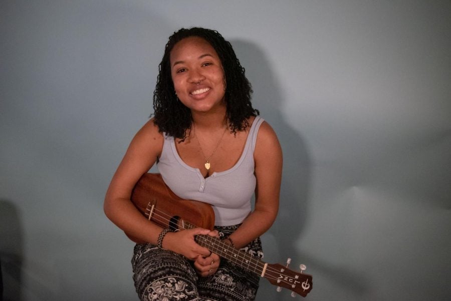 A person smiles with a ukulele in their hands.