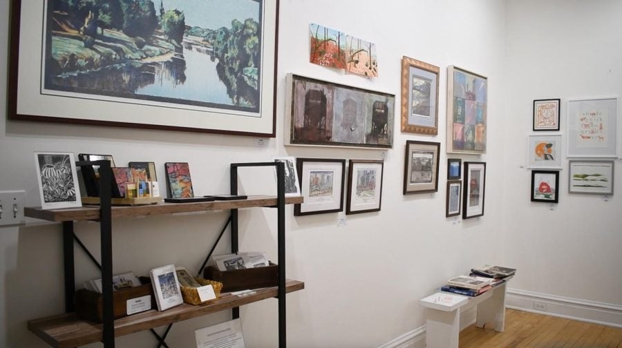 An art gallery with pieces hung up on a white wall.