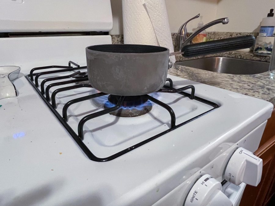 A cooking pot sits on top of a burning gas stove.