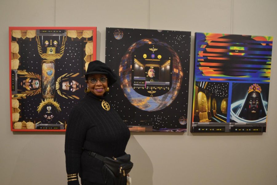 A person in a black dress and hat stands in front of three paintings.