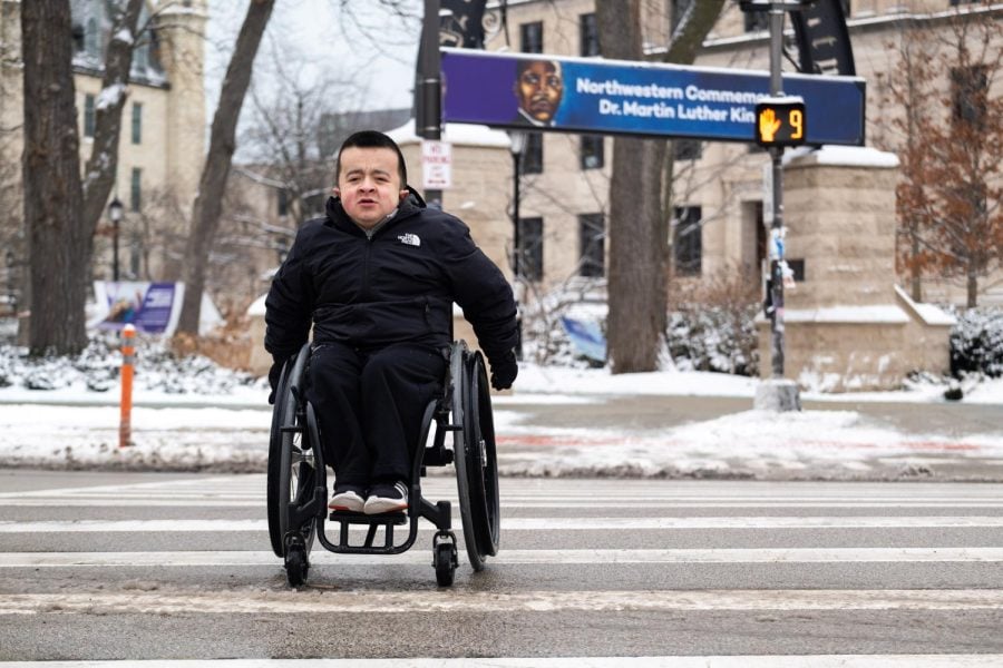 A person in a wheelchair crosses a street.