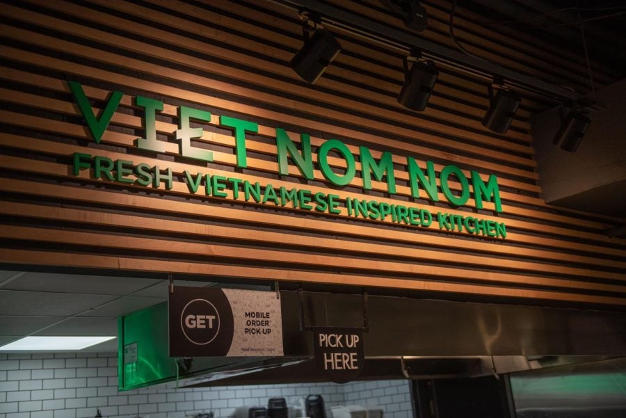 A brown sign with the words “Viet Nom Nom Fresh Vietnamese Inspired Kitchen” in green.