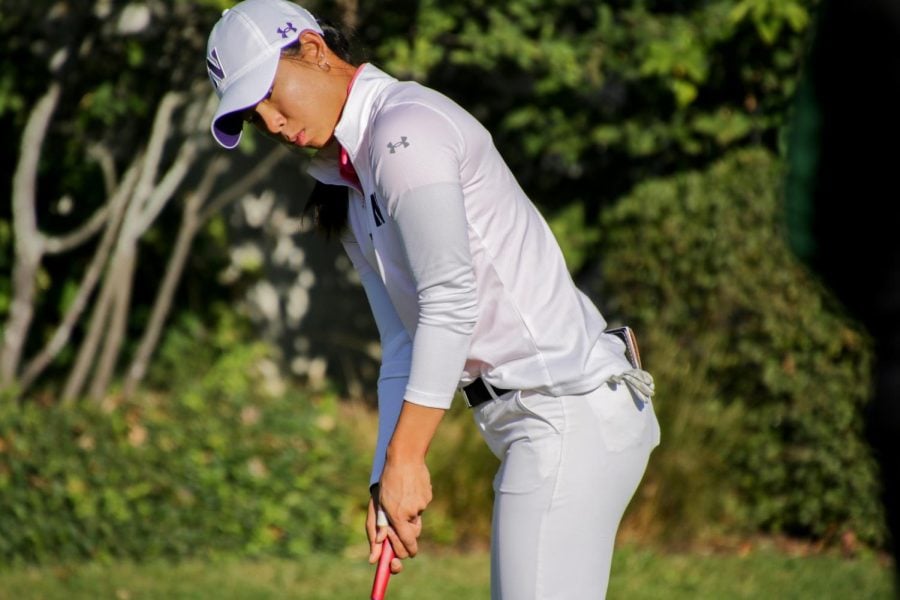 A golfer in white clothes and a white hat holds a golf club.