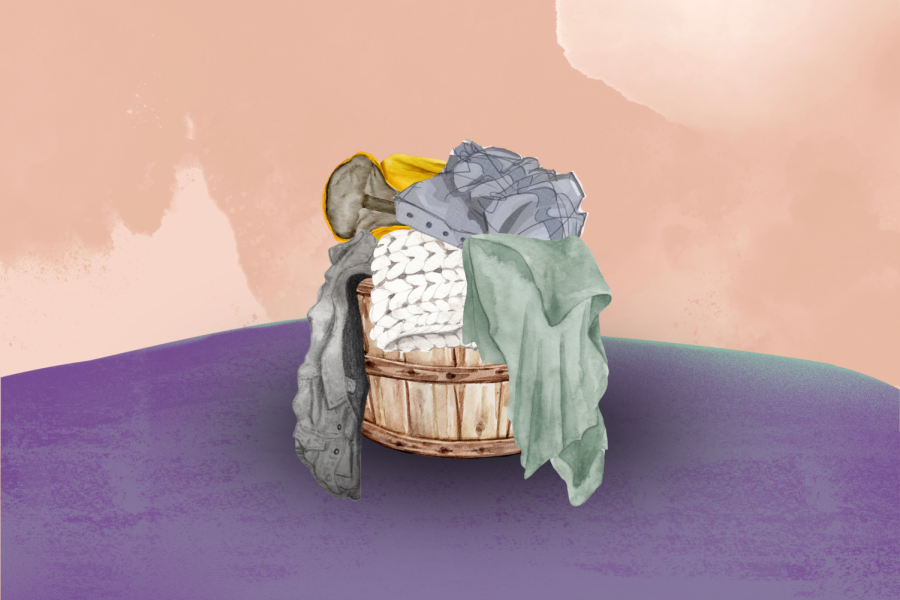 A brown basket with coats and blankets in it.