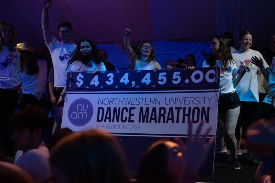 People on a stage hold up a poster board with $434,455 on it.