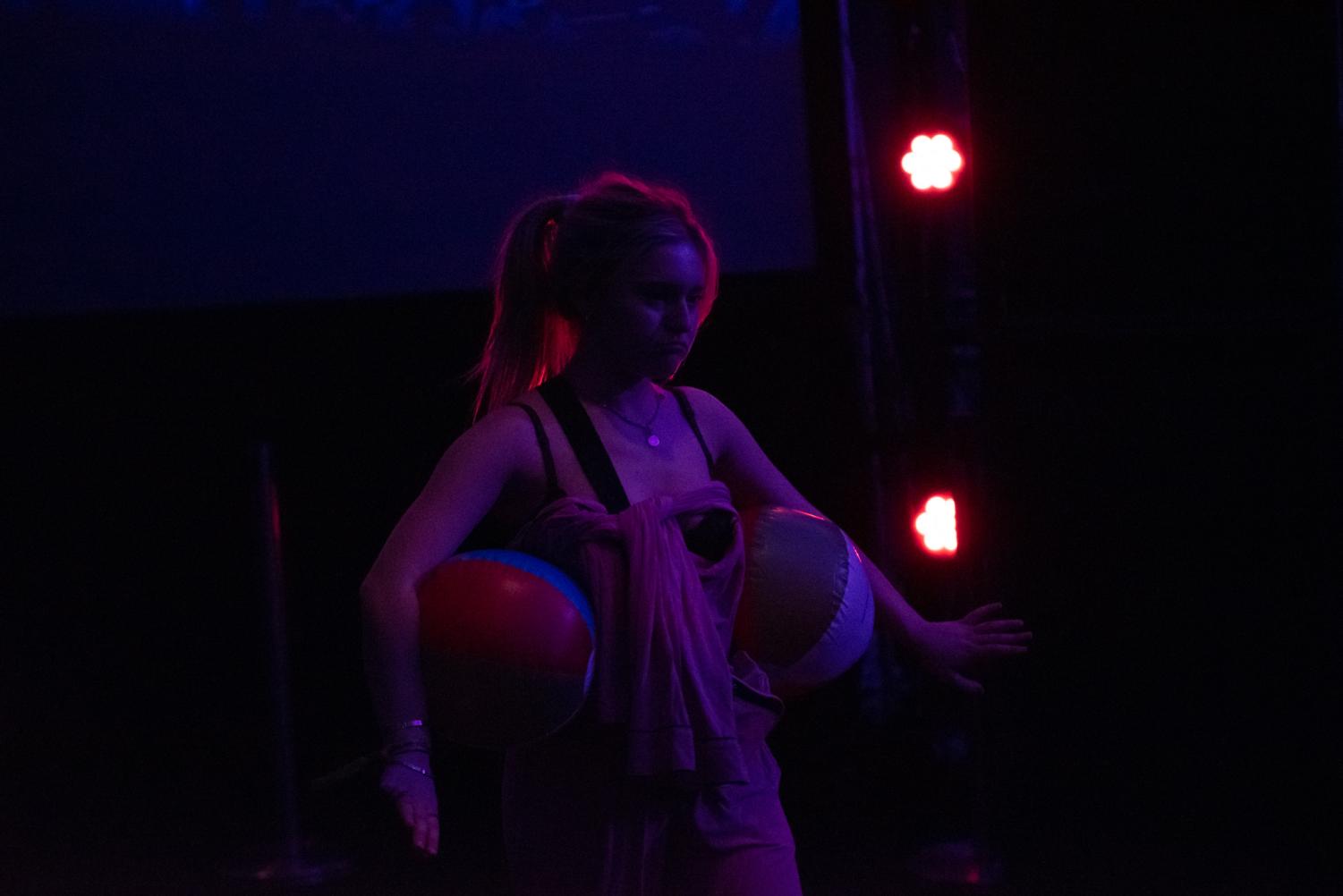 A person holds two beach balls under their arms. 