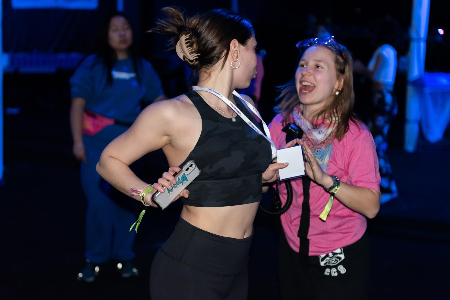 A person in a black sports bra looks back at a person in a pink shirt who is smiling.