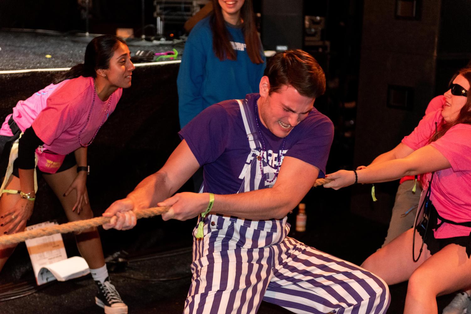 A person in a purple and white overall pulls a rope.
