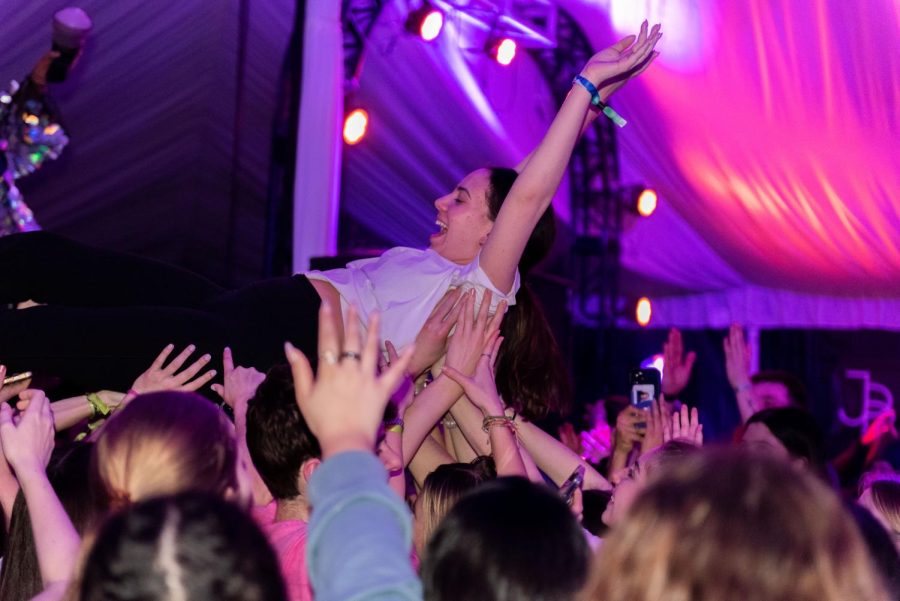A person crowd surfs in purple light.