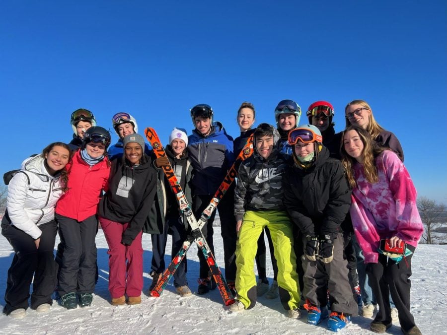 A group of skiers pose on top of a mountain.