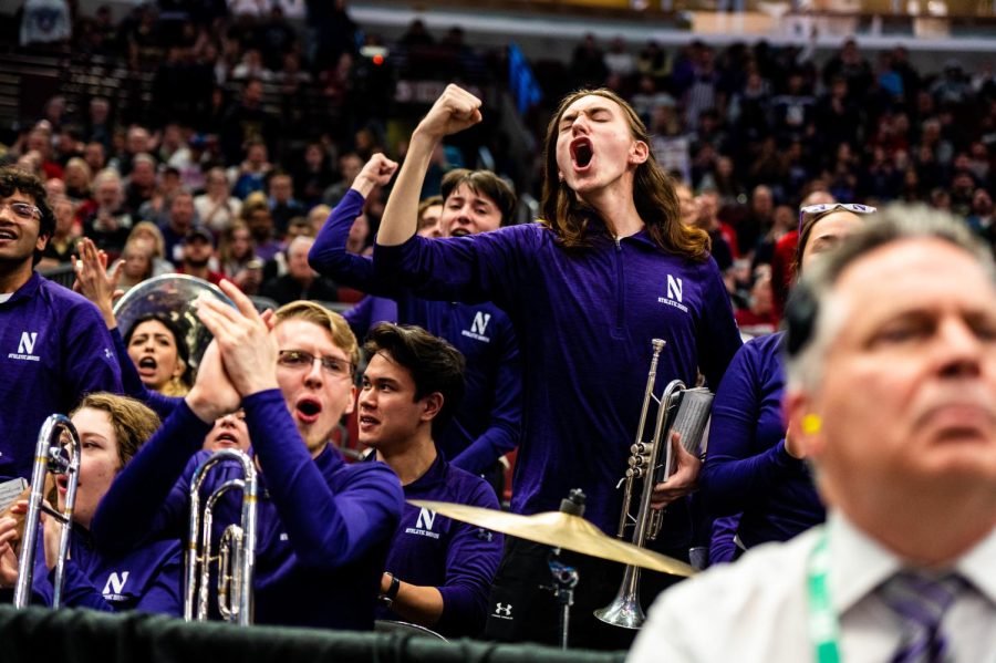 People wearing purple cheer while holding instruments.