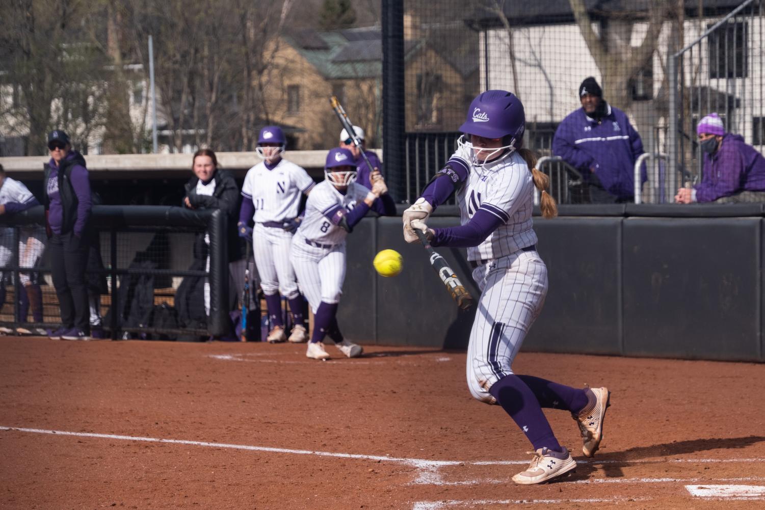Softball+player+in+purple+and+white+uniform+takes+a+swing.