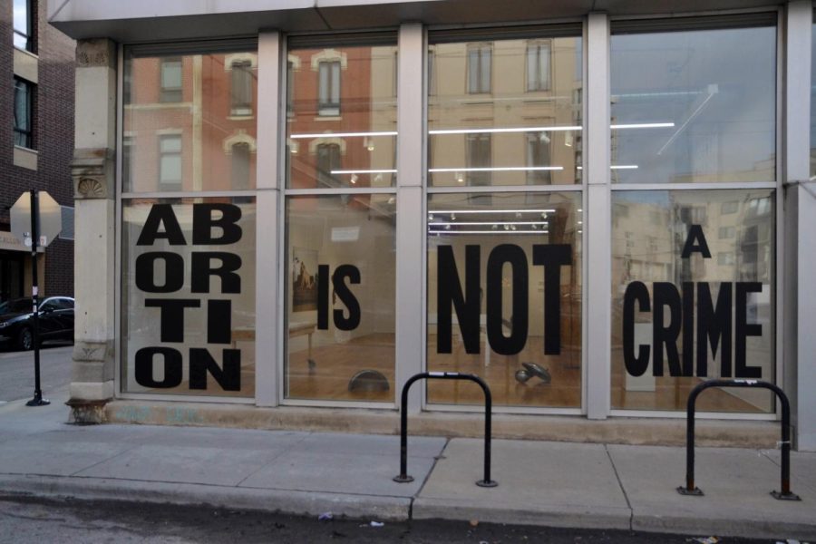 Black letters spell out on the outside glass of an art gallery “Abortion is not a crime”.
