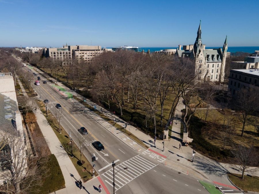 Bird’s eye photograph of the southern end of Northwestern’s campus on a cloudless day. Bisecting the campus is a four-lane road filled with cars driving.