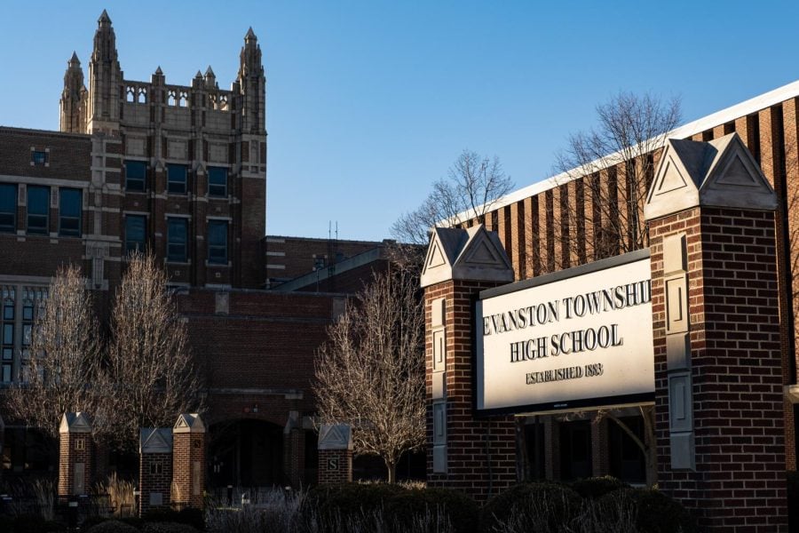 Large red brick school building with trees in front and a sign that reads, “Evanston Township High School.”