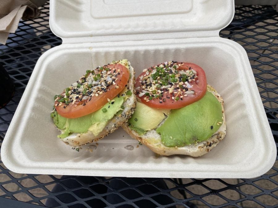 A photograph of the bagel with avocado, tomato and seasoning.