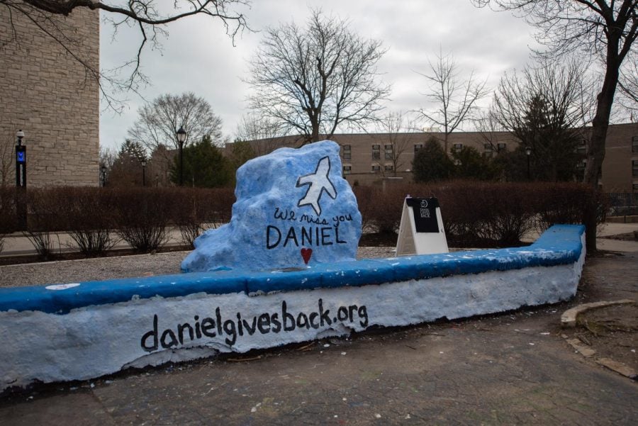 Blue Rock with “We miss you Daniel”, a heart and a plane painted on it. On the ledge of The Rock, the Daniel Gives Back charity website URL is painted on.