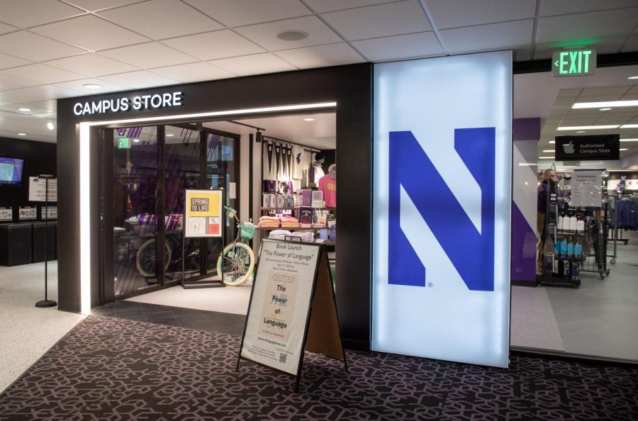 The entrance to the Northwestern campus store. A large, illuminated white panel with a purple “N” next to the entry to a store with shelves of products.