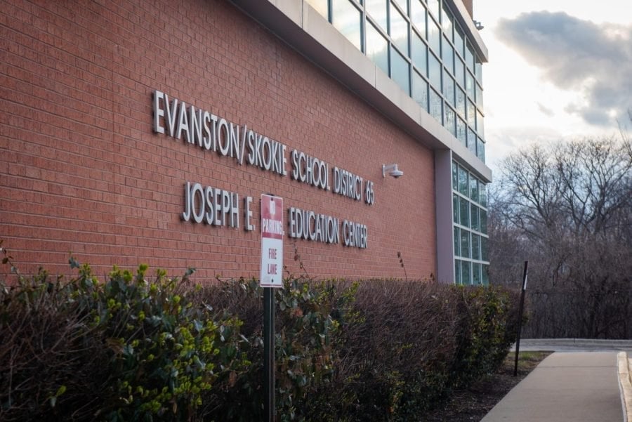 Building with glass and red brick with letters reading “Evanston/Skokie School District 65”.