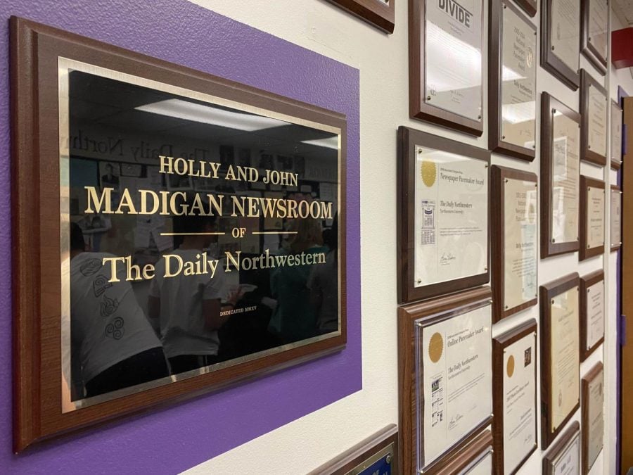 A black-and-gold sign reads, “Holly and John Madigan Newsroom of The Daily Northwestern.”