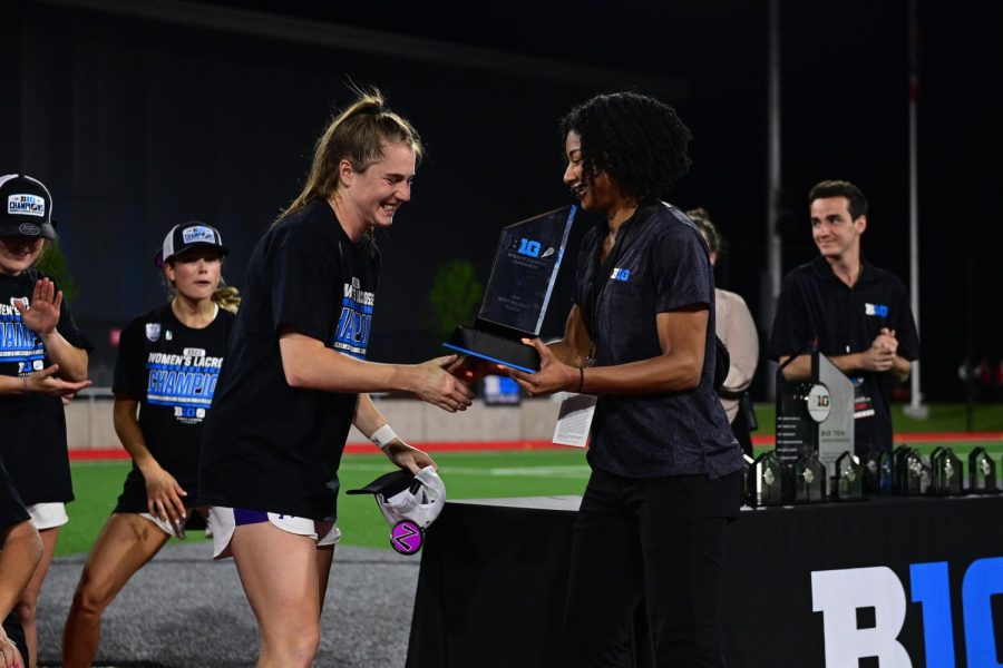 An athlete in a black shirt receives a trophy.