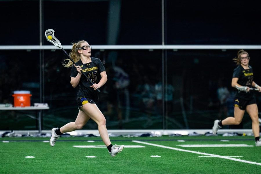 An+athlete+in+a+black+jersey+runs+with+a+lacrosse+ball.