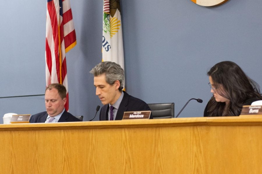 Mayor Daniel Biss sits behind a desk and speaks into a microphone.