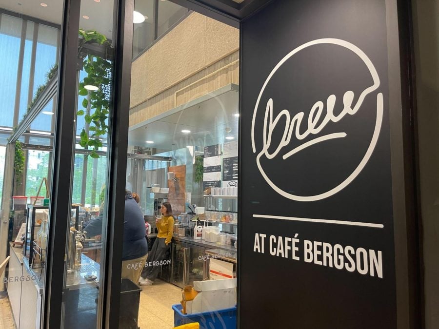 Sign saying “Brew At Café Bergson” in front of glass window.