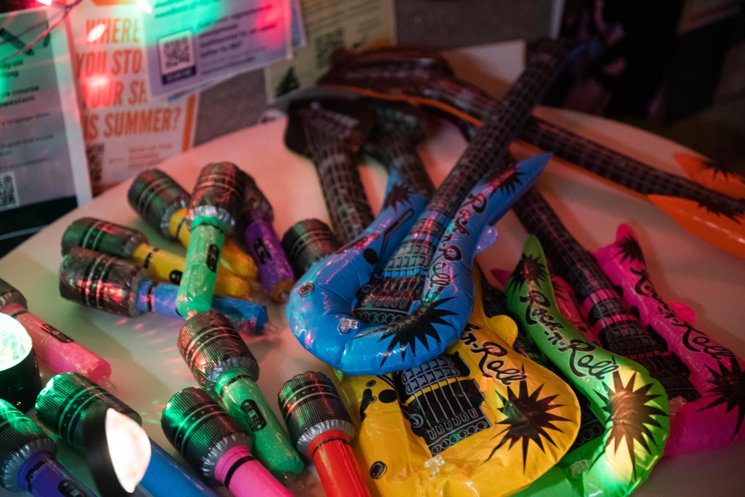 Inflatable guitars and microphones in various colors lie on a white table.