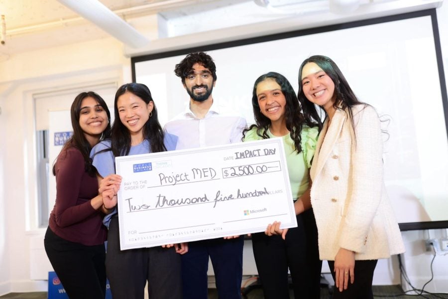 Five people smile while holding a check written out to “Project MED” and awarding “$2,500.”