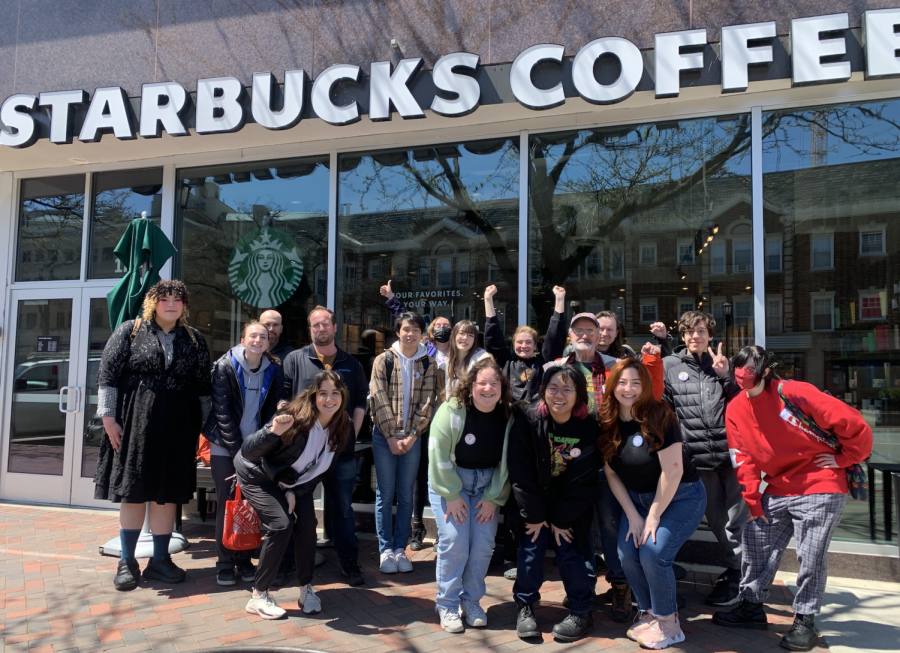 A group of people smiling and posing in front of a store with words that read, “Starbucks Coffee”