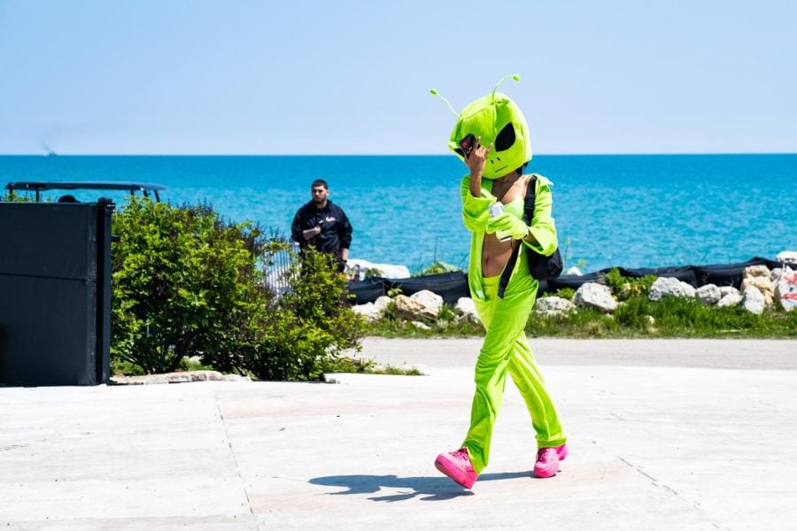 Person in a lime green alien costume walks along the lake.