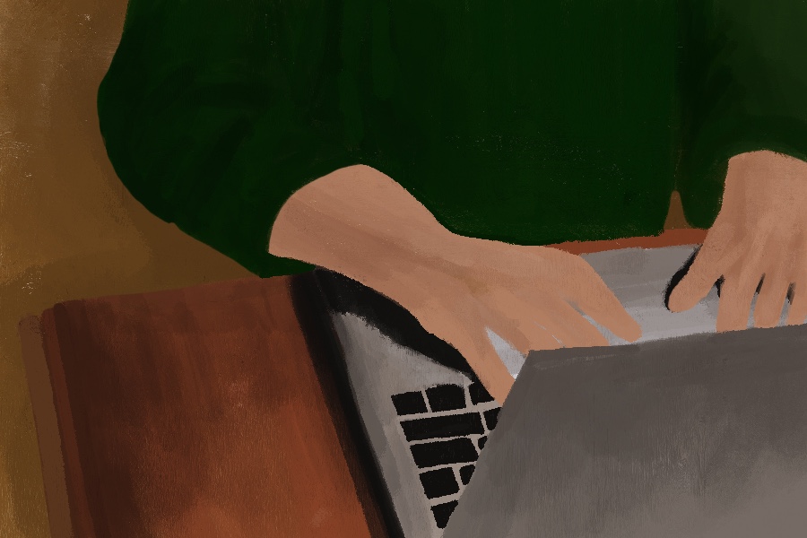 A student in a green shirt typing on a laptop