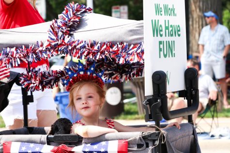 A girl looks out of a cart decorated in red, white and blue tinsel.