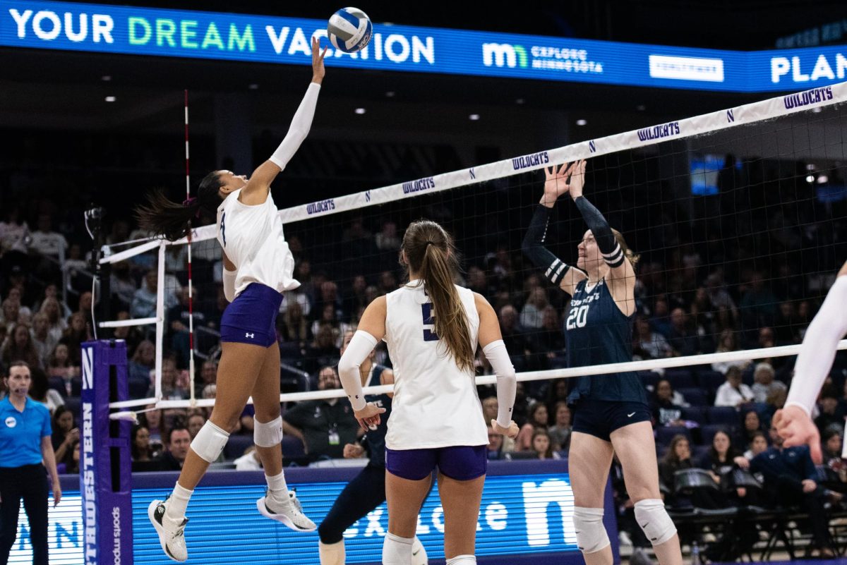 Northwestern player jumps above the net to spike the ball