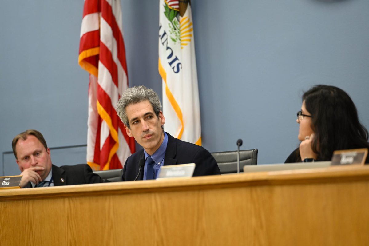Mayor Daniel Biss, wearing a dark suit and blue tie, looks to the side.