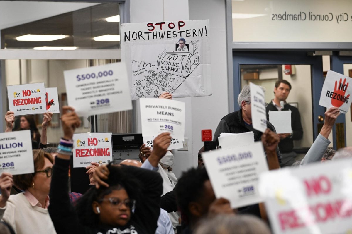 Residents held opposing signs in the Evanston City Council chambers as the body discussed Northwestern’s Rebuild Ryan Field project on Oct. 30.