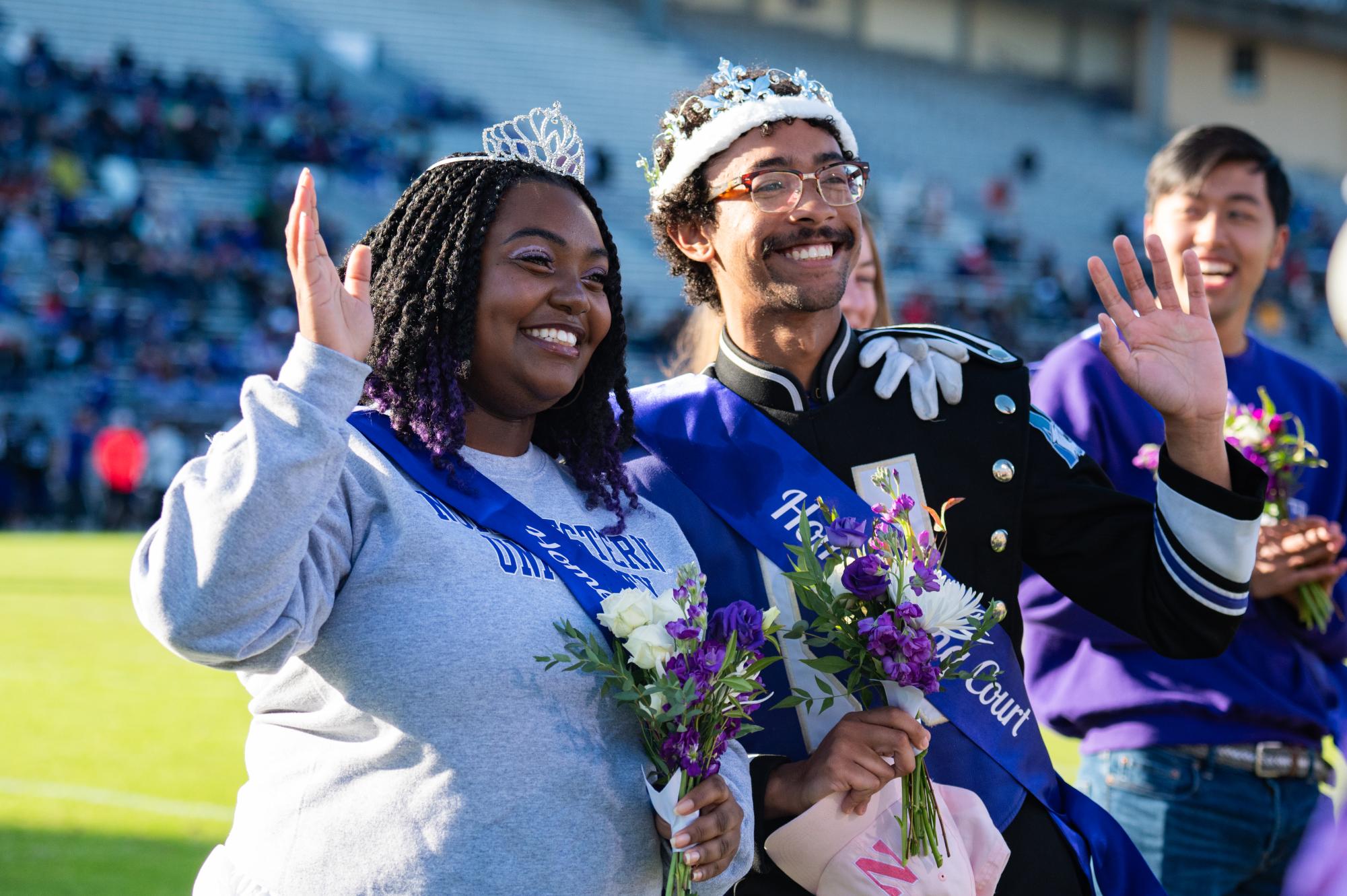 Two people in crowns wave. 